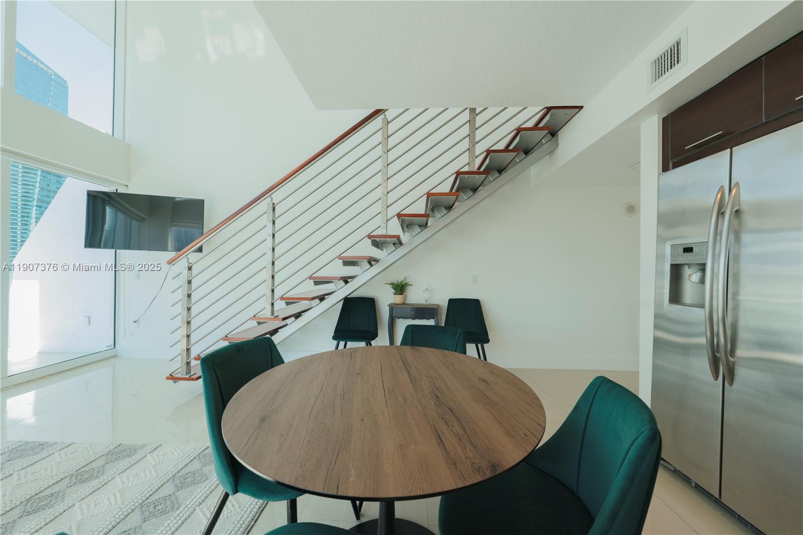 A dining area features a round wooden table, green chairs, and an open staircase — 41 SE 5th St # 1217, Miami FL 33131, MIAMI, FL