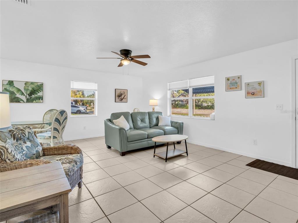 A living room features light tile floors, a teal sofa, and a ceiling fan — 103 E PARK STREET, TARPON SPRINGS, FL