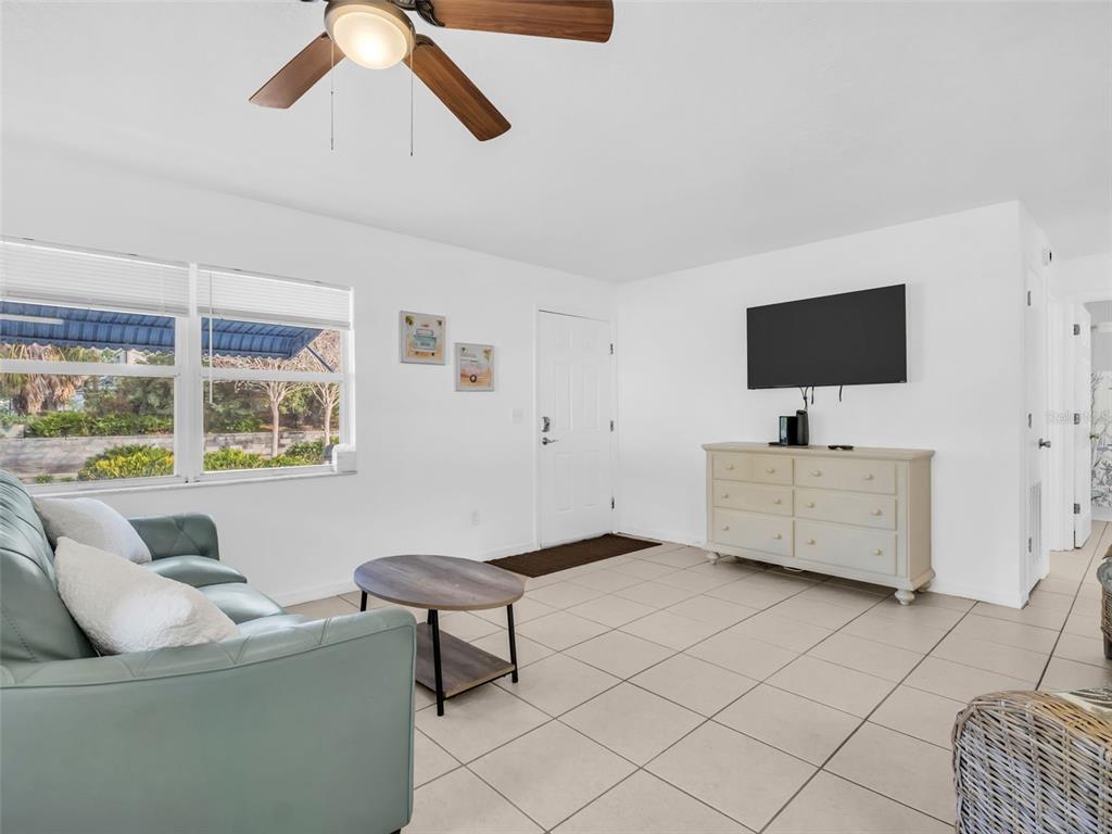 A living room features light tile floors, a teal sofa, a coffee table, and a television — 103 E PARK STREET, TARPON SPRINGS, FL