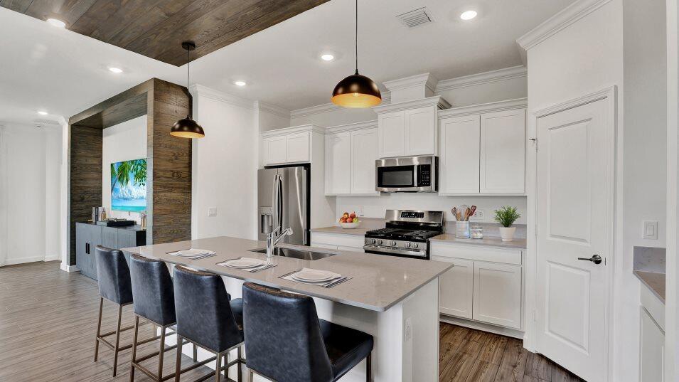 A modern kitchen features white cabinets, a quartz-topped island, and wood-paneled ceiling and wall accents — 1699 Pelican Post Place, FL 33470, FL