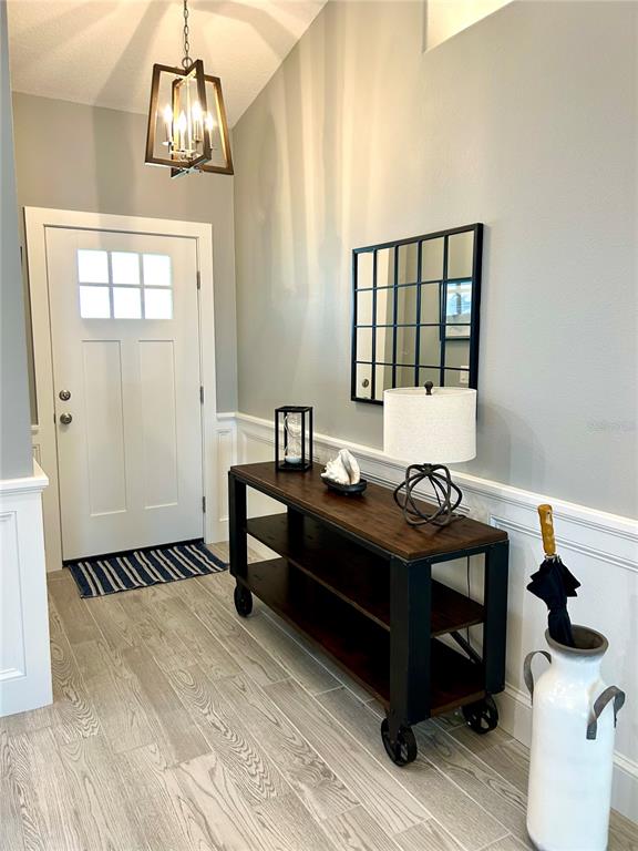 A foyer features a white door, a wooden console table with wheels, and a grid mirror — 35 RIVERSIDE LANE, PALM COAST, FL
