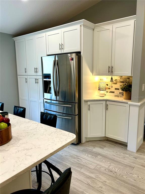 A kitchen features white cabinetry, a stainless steel refrigerator, and a marble-patterned island countertop — 35 RIVERSIDE LANE, PALM COAST, FL