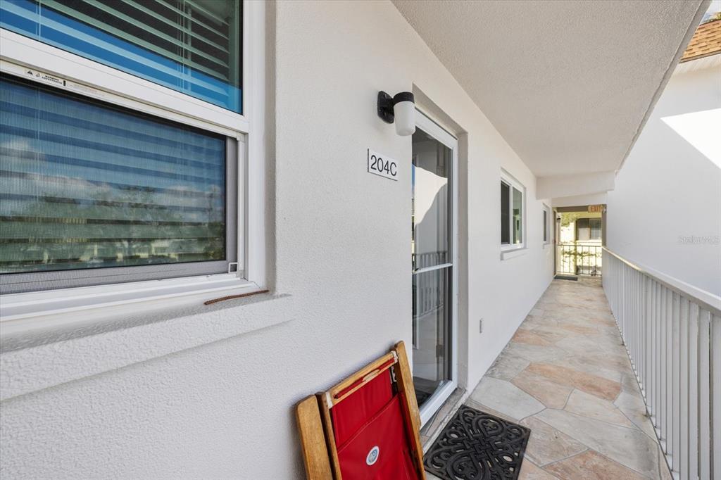 A white exterior walkway features a door labeled 204C, a window, and stone flooring — 116 VISTA HERMOSA CIRCLE UNIT 204C, SARASOTA, FL