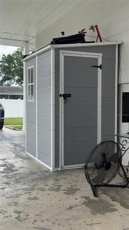A gray resin storage shed sits on a concrete patio under a covered porch — 2523 WEBER STREET, LAKELAND, FL