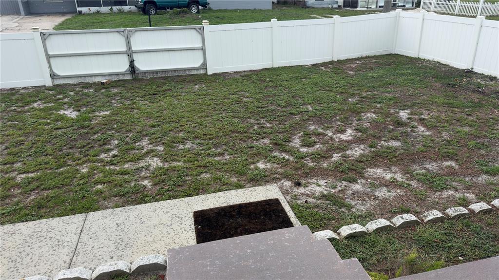 A fenced backyard with a patchy lawn and a concrete patio area — 2523 WEBER STREET, LAKELAND, FL