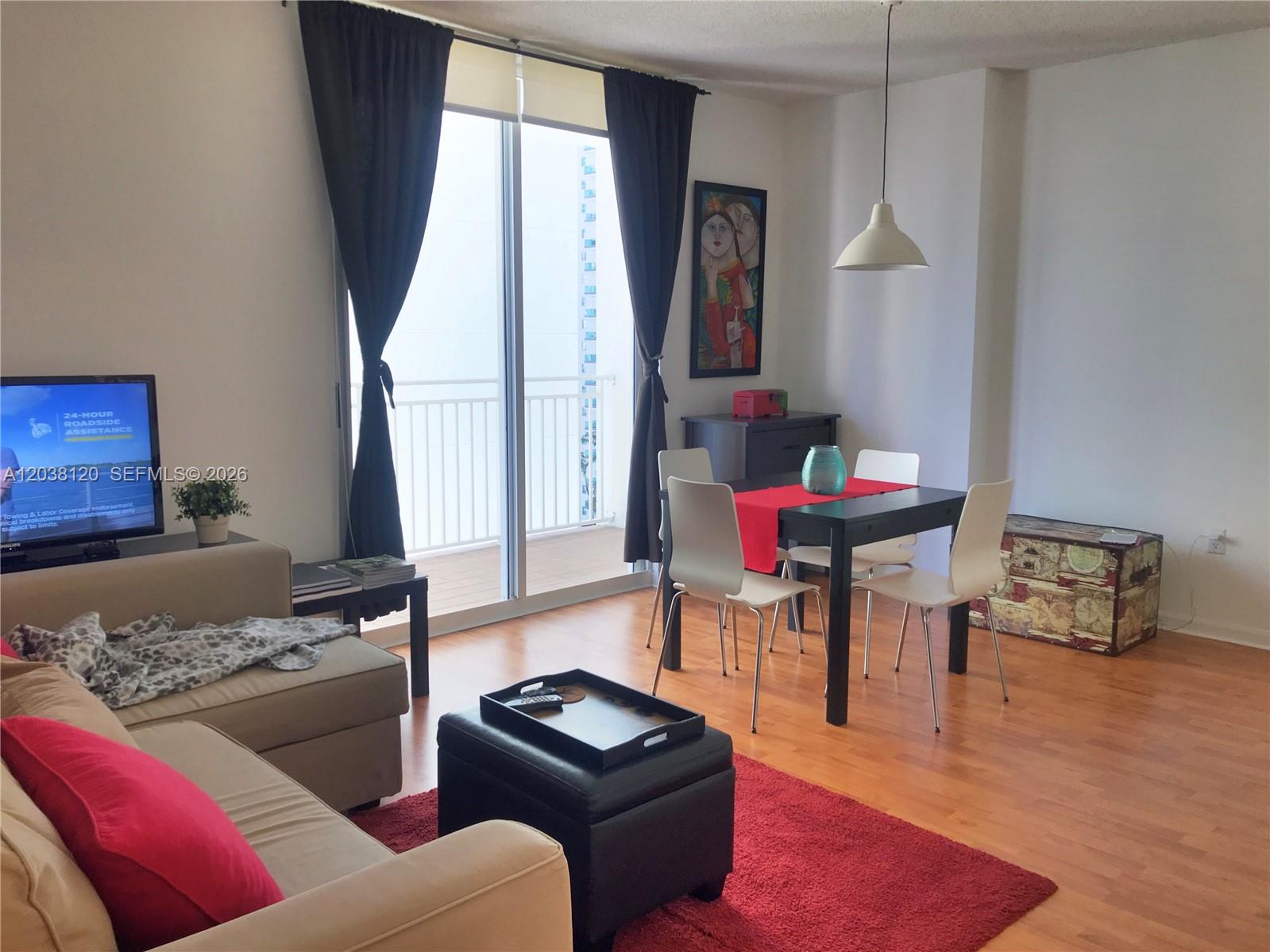 A living and dining area features a beige sofa, a black dining set, and a balcony — 185 SE 14th Ter # 1401, Miami FL 33131, MIAMI, FL