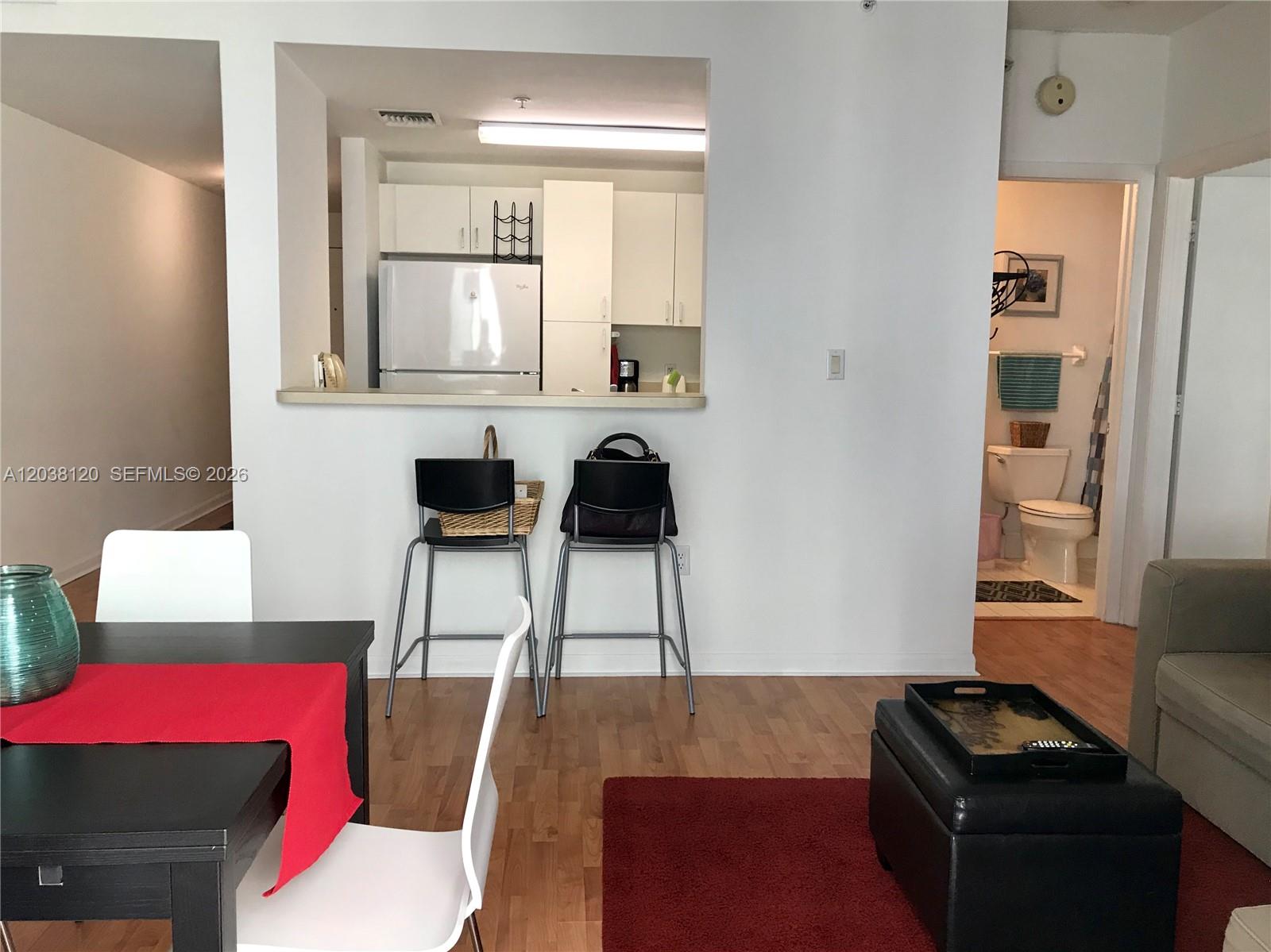 A view of a kitchen pass-through, dining area, and bathroom in an apartment interior — 185 SE 14th Ter # 1401, Miami FL 33131, MIAMI, FL