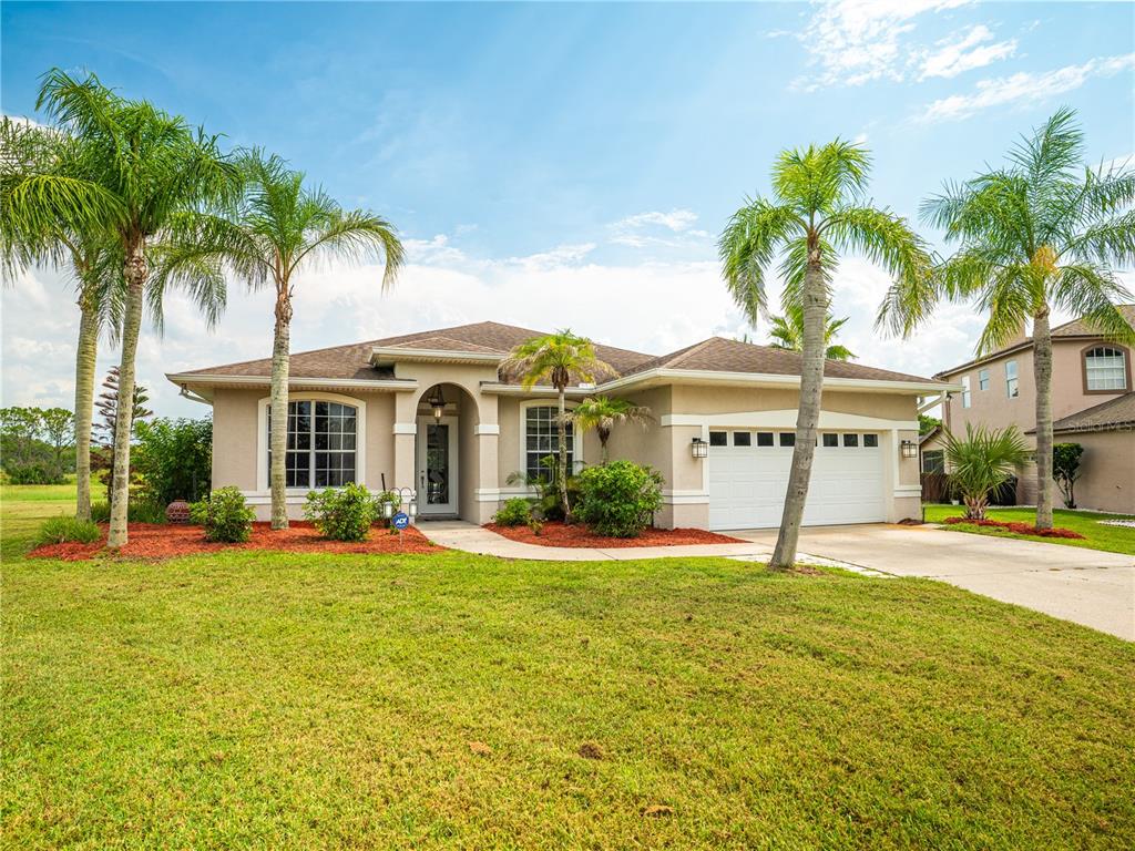 A single-story suburban house with a two-car garage, palm trees, and a grassy front yard — 13644 DORNOCH DRIVE, ORLANDO, FL