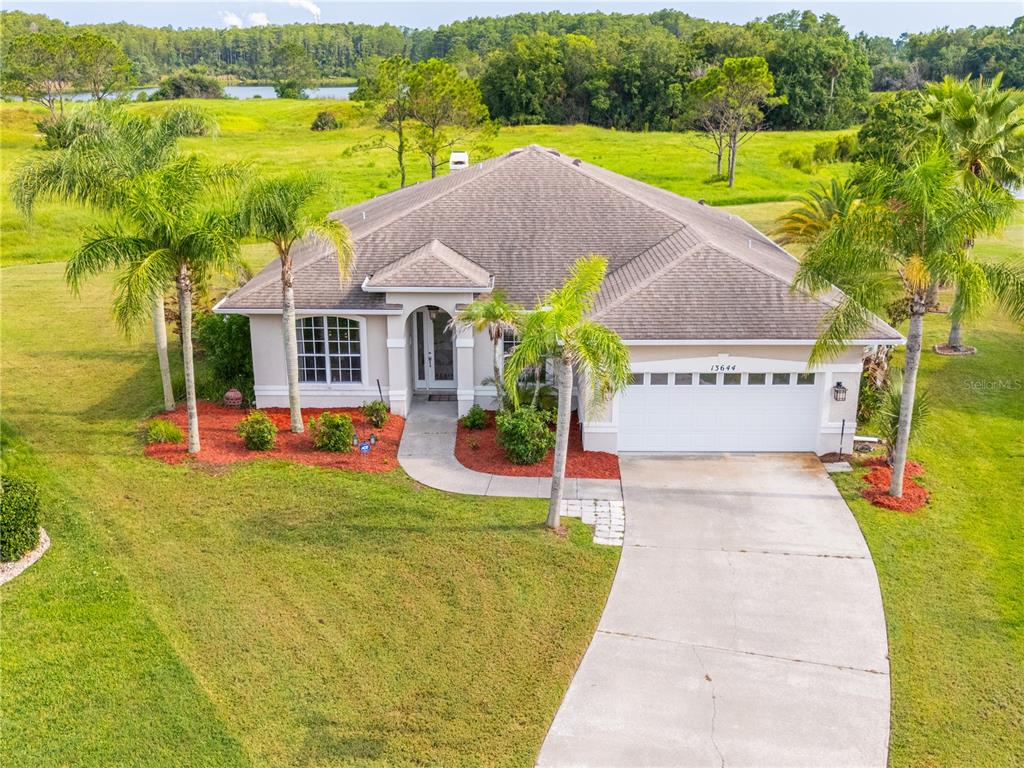 An aerial view of a single-story suburban house with a white garage and palm trees — 13644 DORNOCH DRIVE, ORLANDO, FL