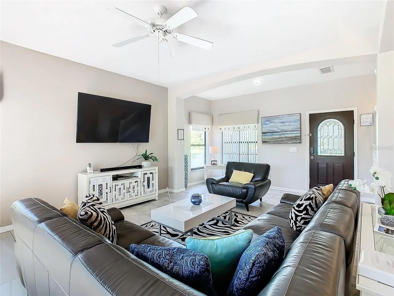 A living room features a large sectional sofa, a television, and a ceiling fan — 16708 Lazy Breeze Loop # 16708, Clermont FL 34714, CLERMONT, FL