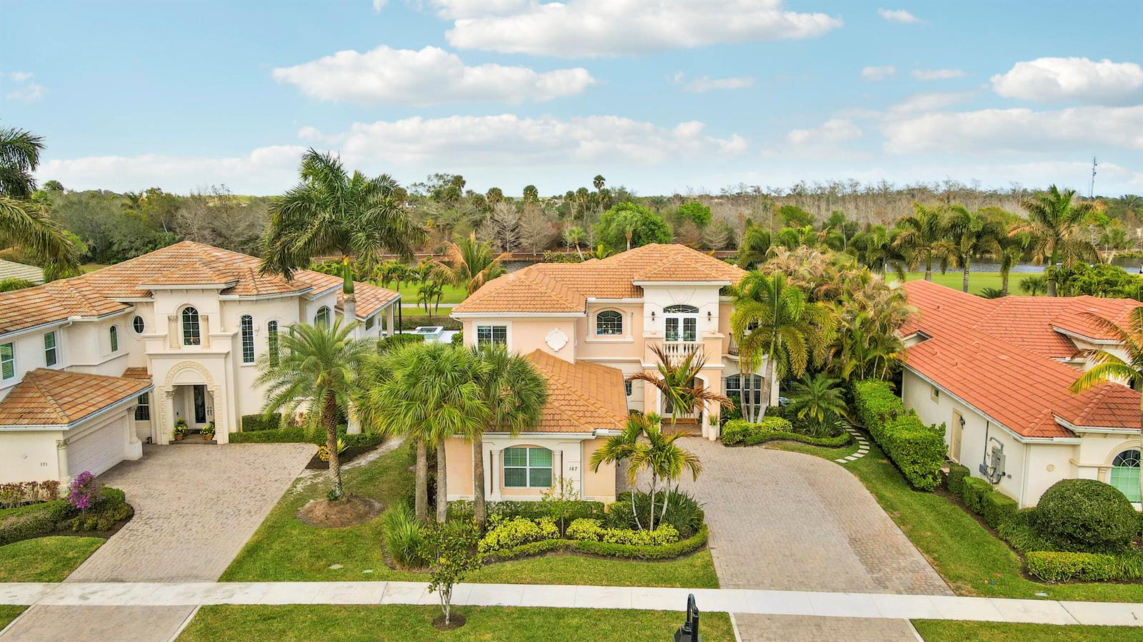 An aerial view of three large, light-colored houses with terracotta tile roofs and palm trees — 167 Rosalia Court S, Jupiter FL 33478, JUPITER, FL