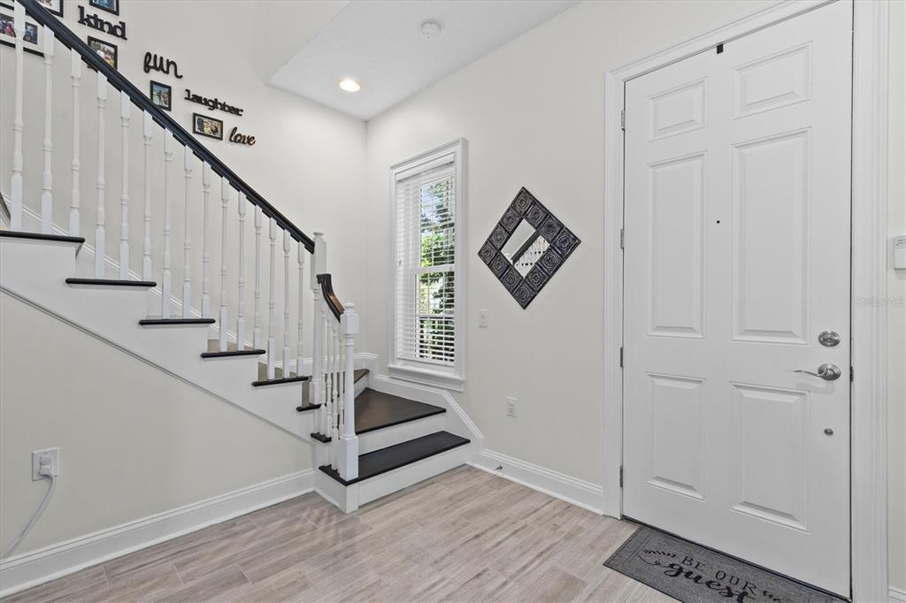 An entryway features a staircase with dark wood treads, white railings, and light tile flooring — 480 GILMAN PLACE N, ST PETERSBURG, FL