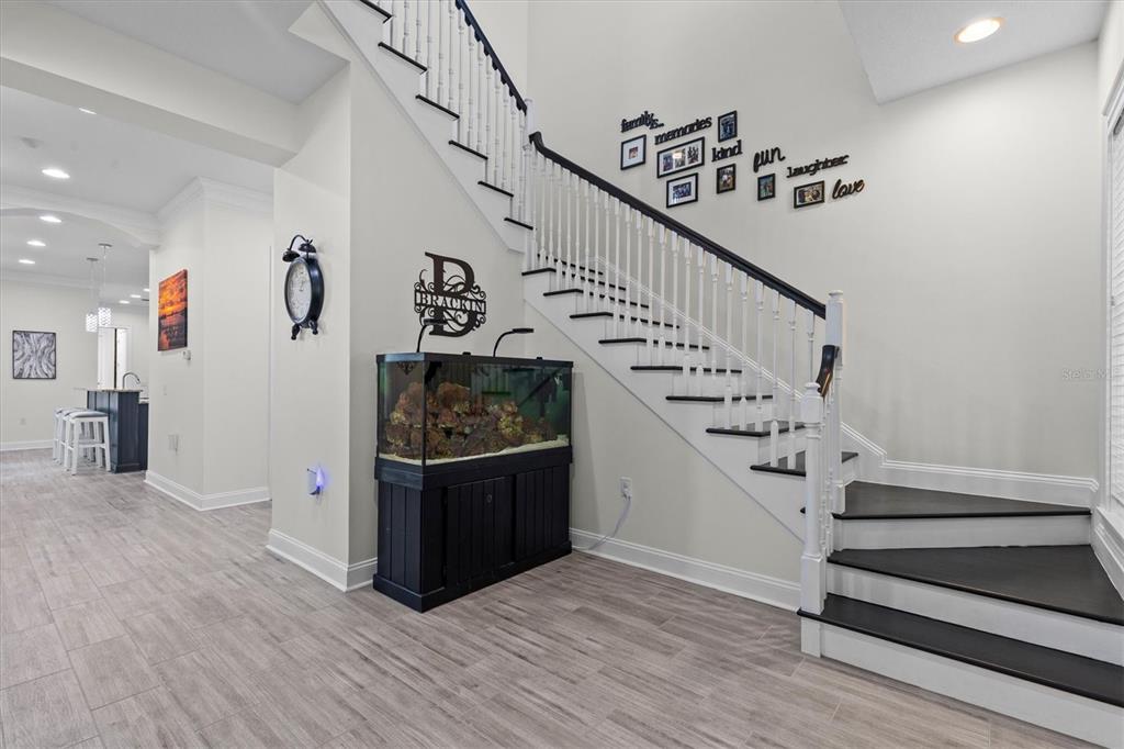 A staircase with black treads and white railings stands next to a large fish tank — 480 GILMAN PLACE N, ST PETERSBURG, FL