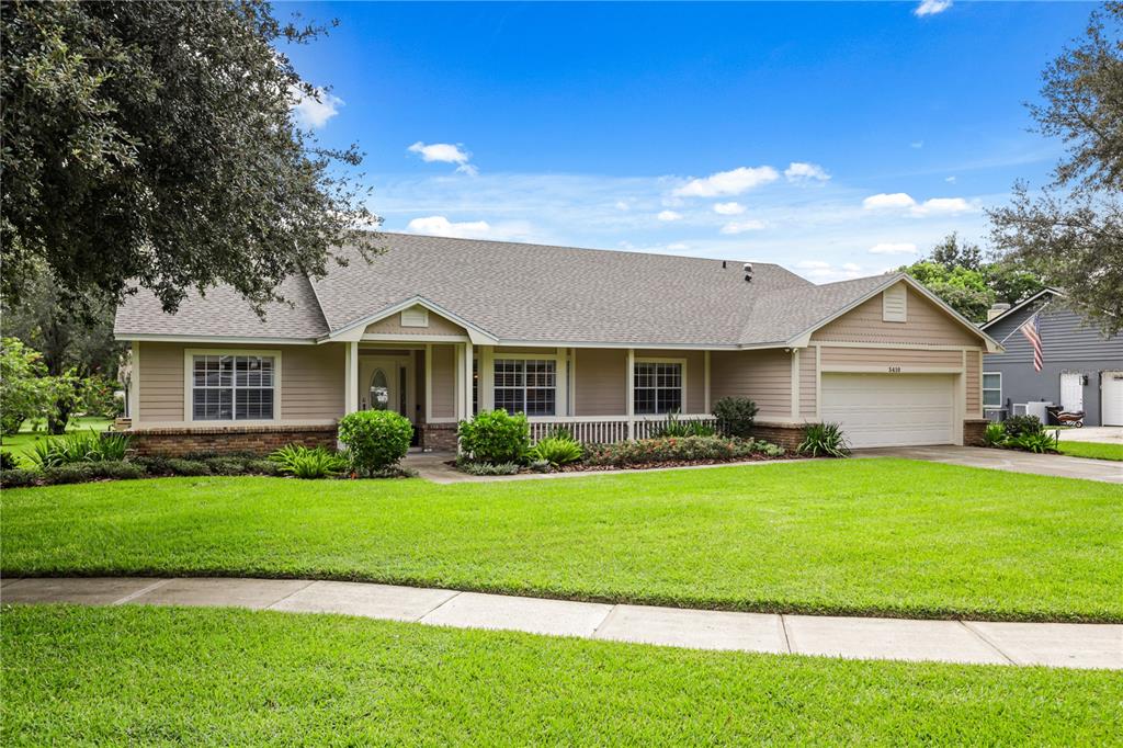 A single-story house with tan siding, a front porch, and a two-car garage — 5410 RUSTIC PINE COURT, ORLANDO, FL