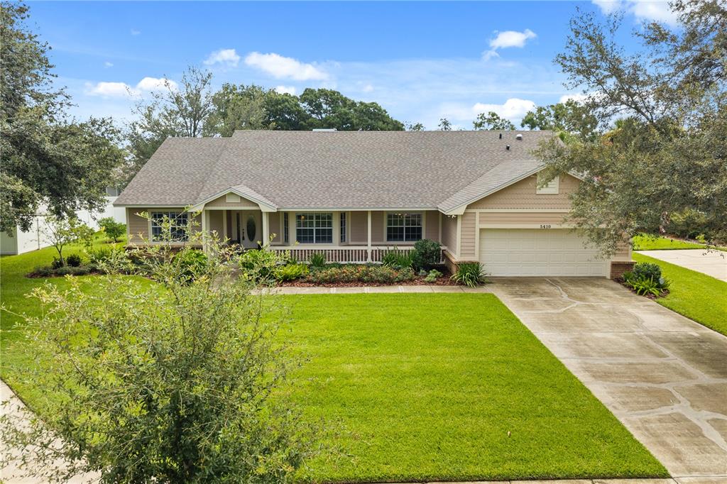 A single-story house with a beige exterior, a front porch, and an attached two-car garage — 5410 RUSTIC PINE COURT, ORLANDO, FL