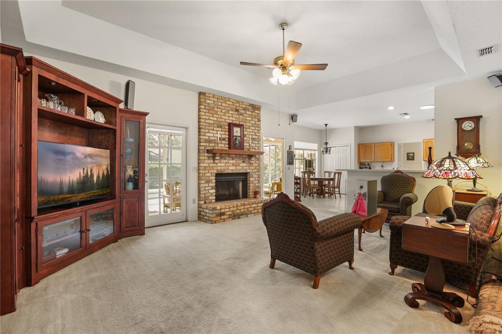 A living room features a brick fireplace, a large wooden entertainment center, and carpeted floors — 5410 RUSTIC PINE COURT, ORLANDO, FL