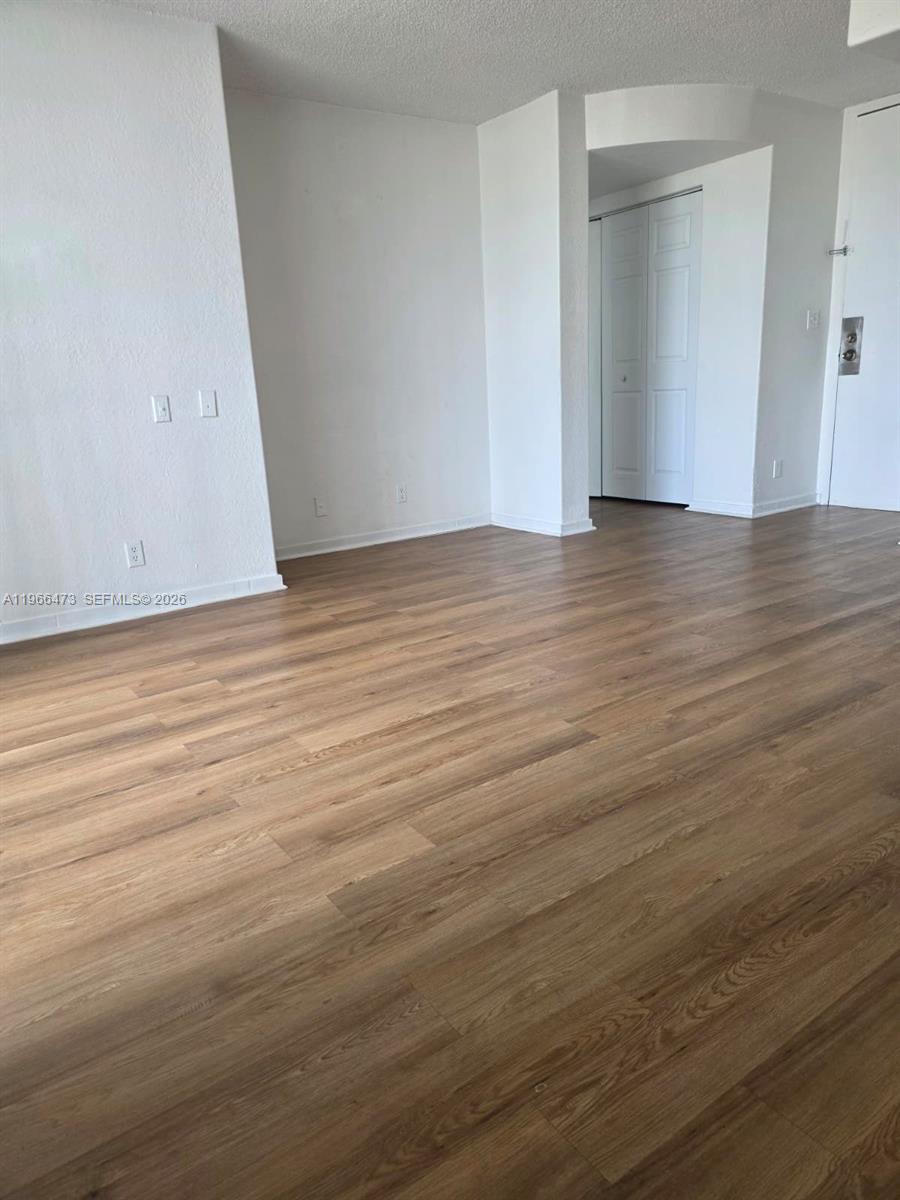 An empty room features light wood-look flooring and white walls with a closet — 16450 NW 2nd Ave # 214, Miami FL 33169, MIAMI, FL