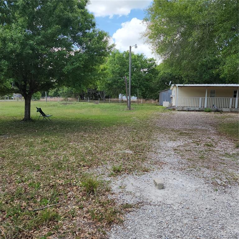A gravel driveway leads to a mobile home with a porch next to a large tree — 26739 FOAMFLOWER BOULEVARD, WESLEY CHAPEL, FL