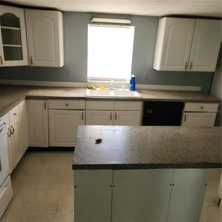 A kitchen features white cabinets, a central island, and a window above the sink — 26739 FOAMFLOWER BOULEVARD, WESLEY CHAPEL, FL