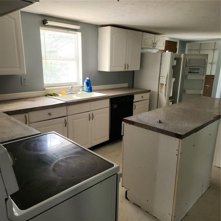 A kitchen with white cabinets, a central island, a sink, and a black dishwasher — 26739 FOAMFLOWER BOULEVARD, WESLEY CHAPEL, FL