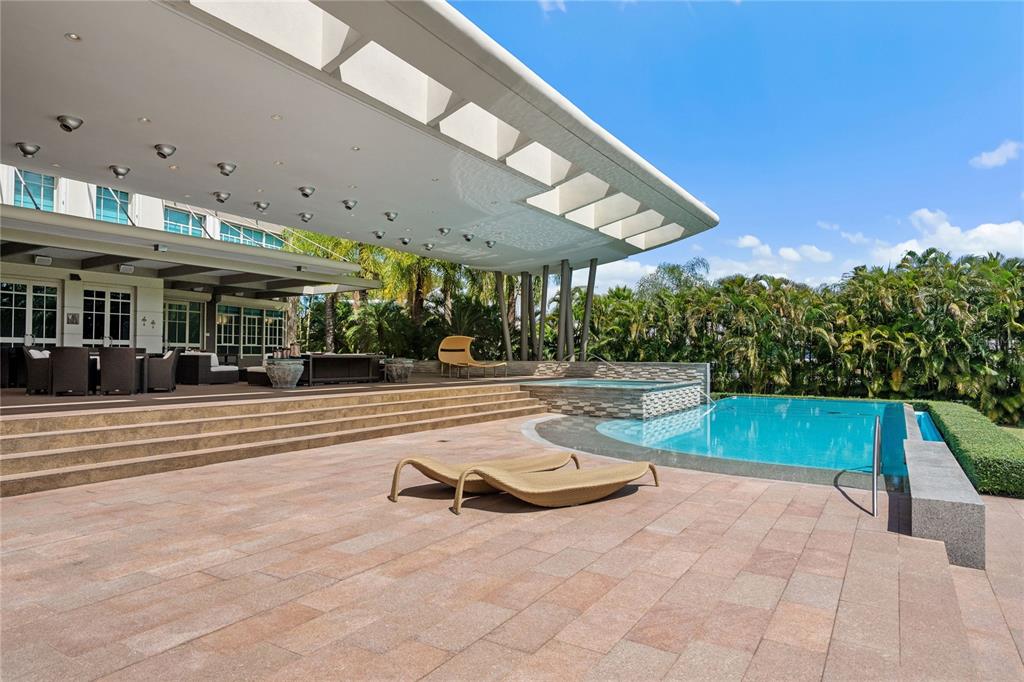 A modern patio features a large covered seating area, stone steps, and an infinity pool — 9 CASTAÑA STREET, GUAYNABO, PR