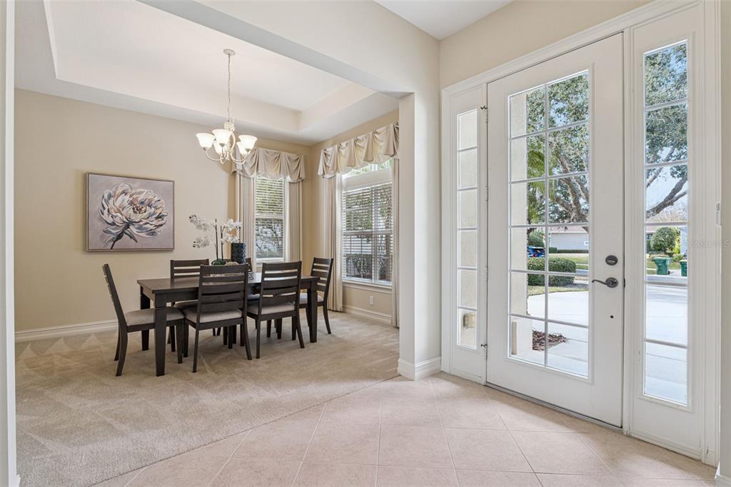 A dining area with carpeted floors and a chandelier sits adjacent to a tiled entryway — 112 BELLINGRATH TERRACE, DELAND, FL