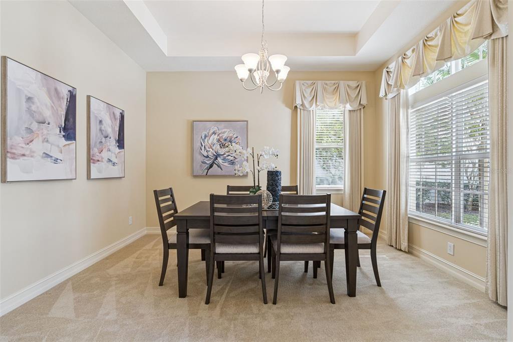 A dining room with a dark wood table, six chairs, carpeted floors, and a chandelier — 112 BELLINGRATH TERRACE, DELAND, FL