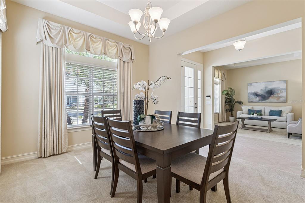 A dining room with a dark wood table and chairs sits adjacent to a living area — 112 BELLINGRATH TERRACE, DELAND, FL