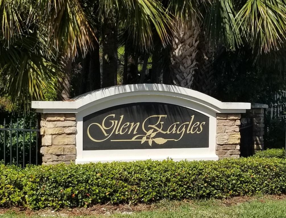 A stone and white monument sign for the Glen Eagles community stands behind a hedge — 104 OLD MILL POND ROAD, PALM HARBOR, FL