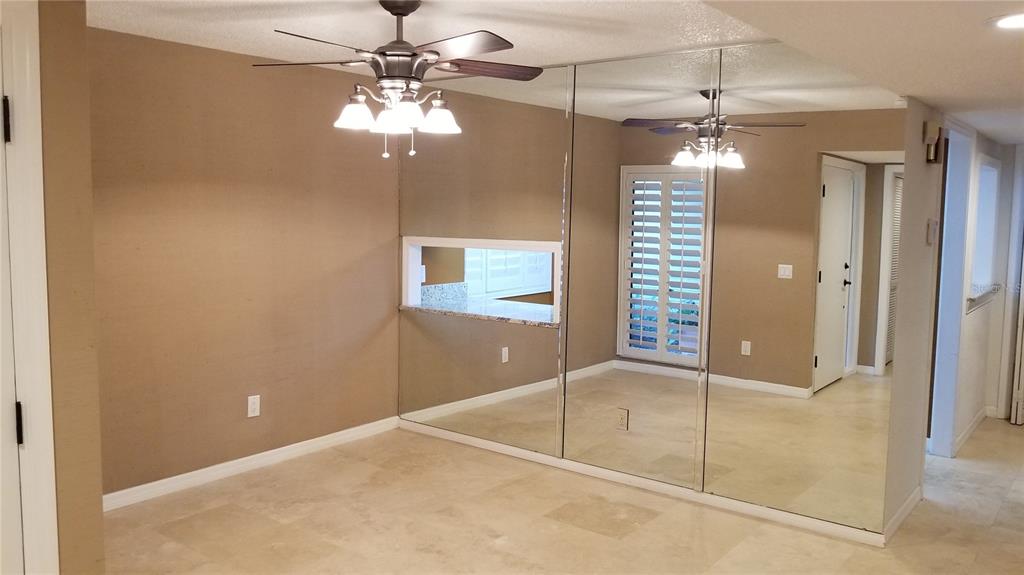 A dining room with beige walls, tile flooring, a ceiling fan, and a mirrored wall — 104 OLD MILL POND ROAD, PALM HARBOR, FL