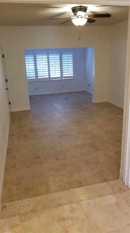 An interior view shows a tiled room leading into a sunlit space with plantation shutters — 104 OLD MILL POND ROAD, PALM HARBOR, FL