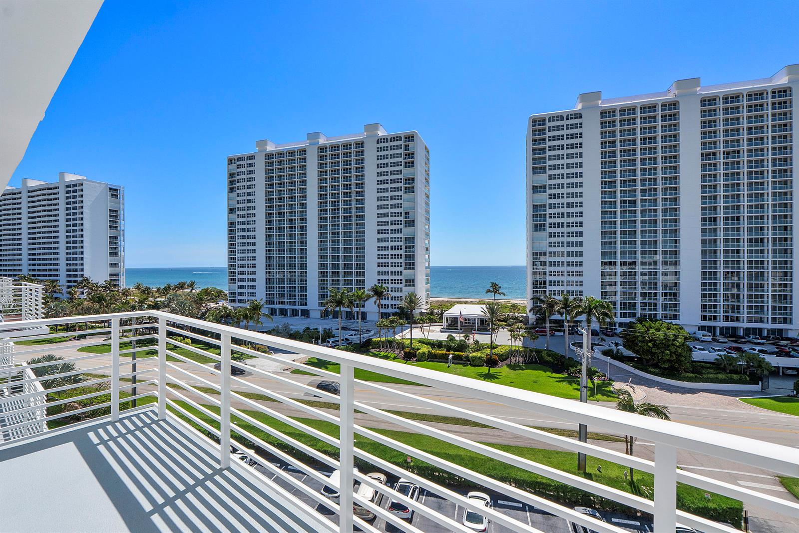 A balcony view overlooking a road, palm trees, and high-rise buildings near the ocean — 2851 S Ocean Boulevard, Boca Raton FL 33432, BOCA RATON, FL