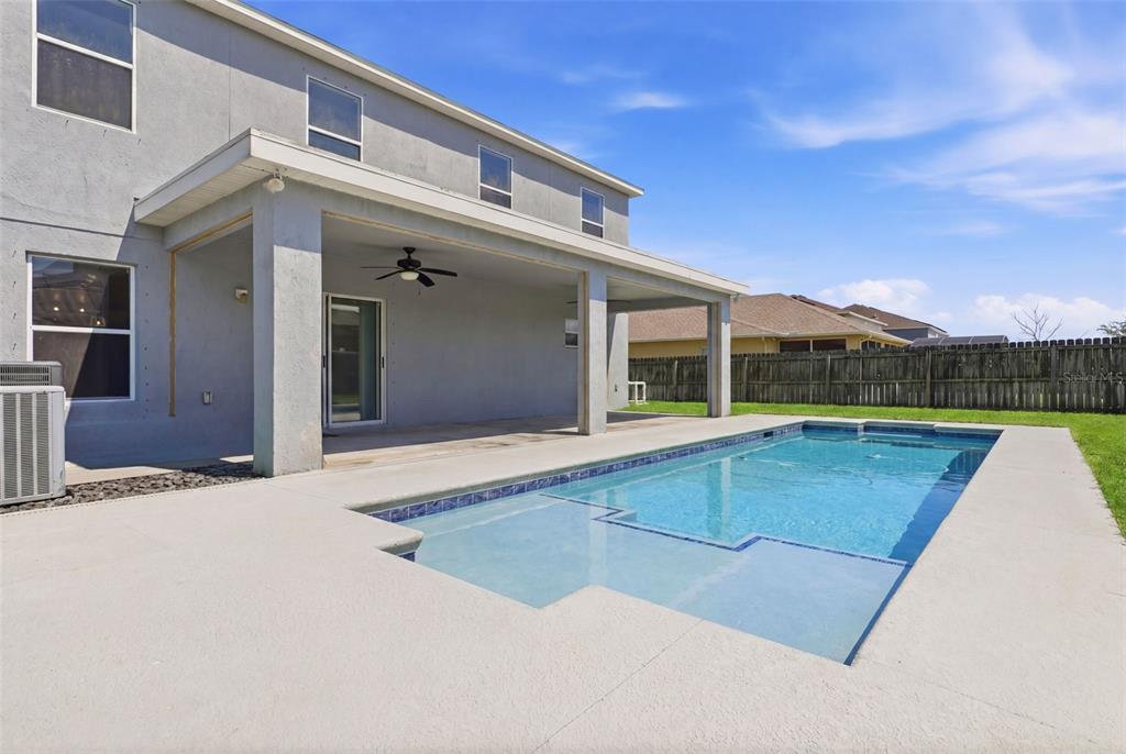 A backyard features a covered patio, a swimming pool, and a wooden privacy fence — 3356 SLATE STREET, WEST MELBOURNE, FL