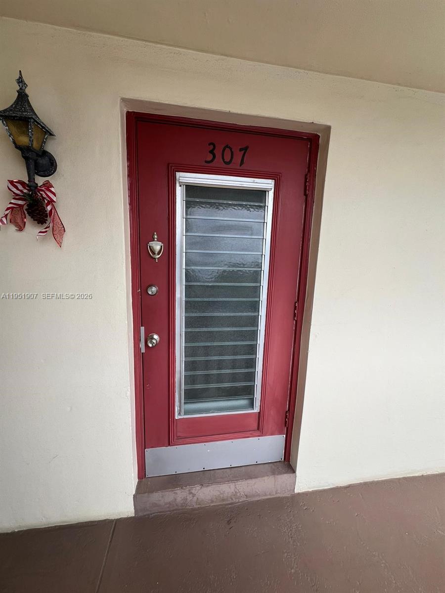 A red front door with a vertical glass louvered window is labeled with the number 307 — 4299 NW 16th St # 307, Lauderhill FL 33313, LAUDERHILL, FL