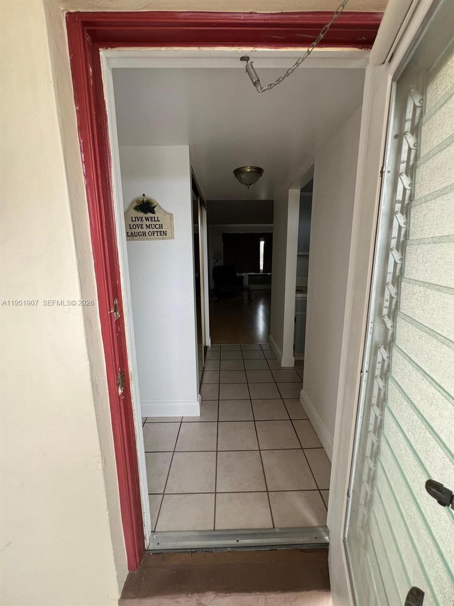 A tiled hallway leads from an open doorway toward a living area with wood flooring — 4299 NW 16th St # 307, Lauderhill FL 33313, LAUDERHILL, FL