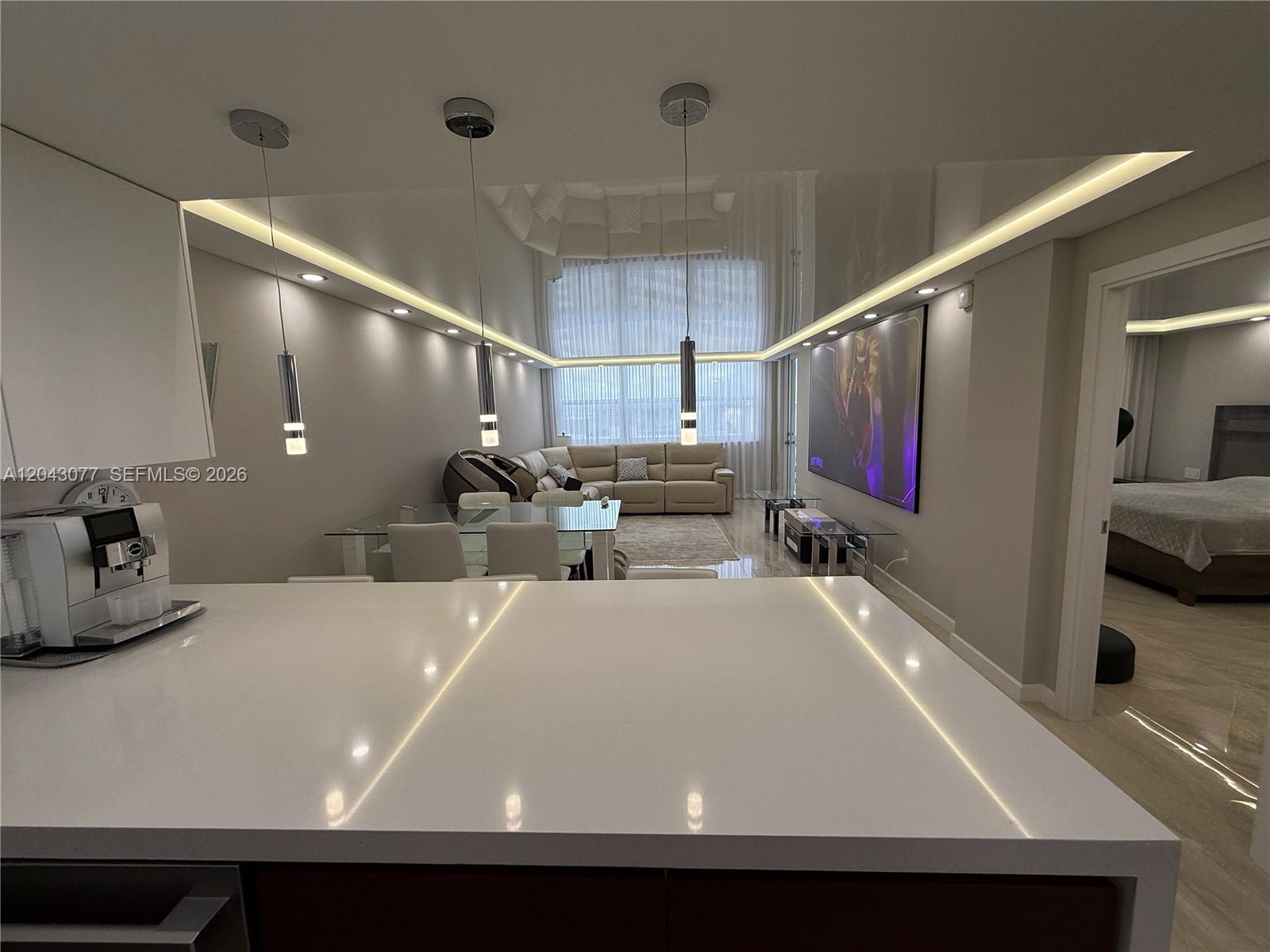 A modern kitchen island overlooks an open-concept living and dining area with recessed lighting — 1849 S Ocean Dr, Hallandale Beach FL 33009, HALLANDALE BEACH, FL