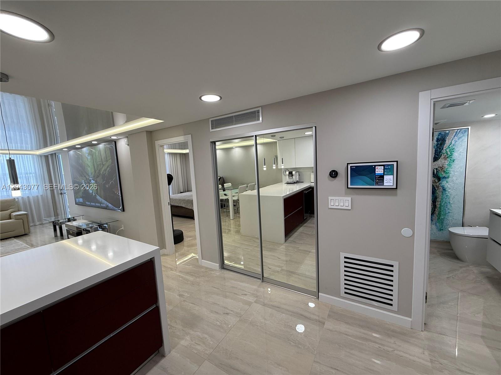 A modern interior features a kitchen with mirrored sliding doors, tile flooring, and recessed lighting — 1849 S Ocean Dr, Hallandale Beach FL 33009, HALLANDALE BEACH, FL