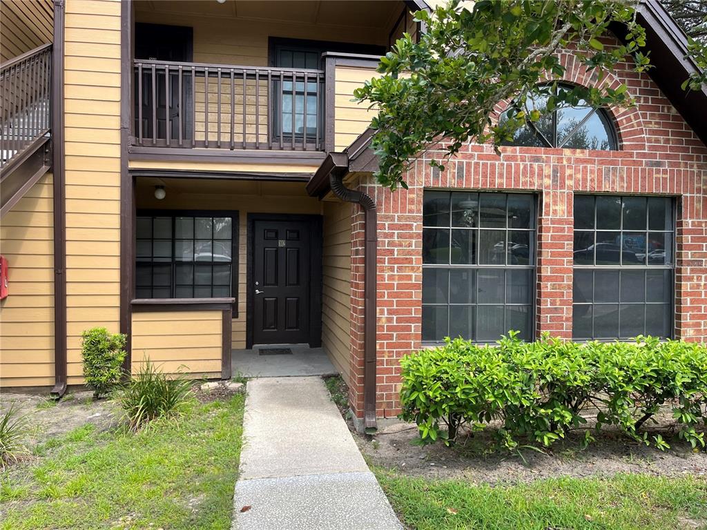 The exterior of a two-story apartment building features brick and yellow siding with a walkway — 315 LAKEPOINTE DRIVE UNIT 102, ALTAMONTE SPRINGS, FL