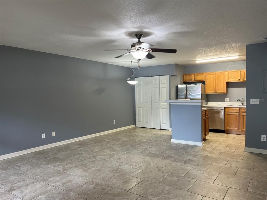 An open-concept room features gray walls, tile flooring, a ceiling fan, and a small kitchen — 315 LAKEPOINTE DRIVE UNIT 102, ALTAMONTE SPRINGS, FL