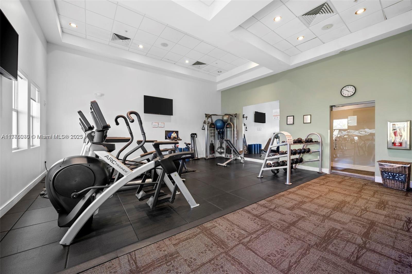 This gym features rubber flooring, cardio machines, a dumbbell rack, and a wall-mounted clock — 5300 NW 87th Ave # 115, Doral FL 33178, DORAL, FL