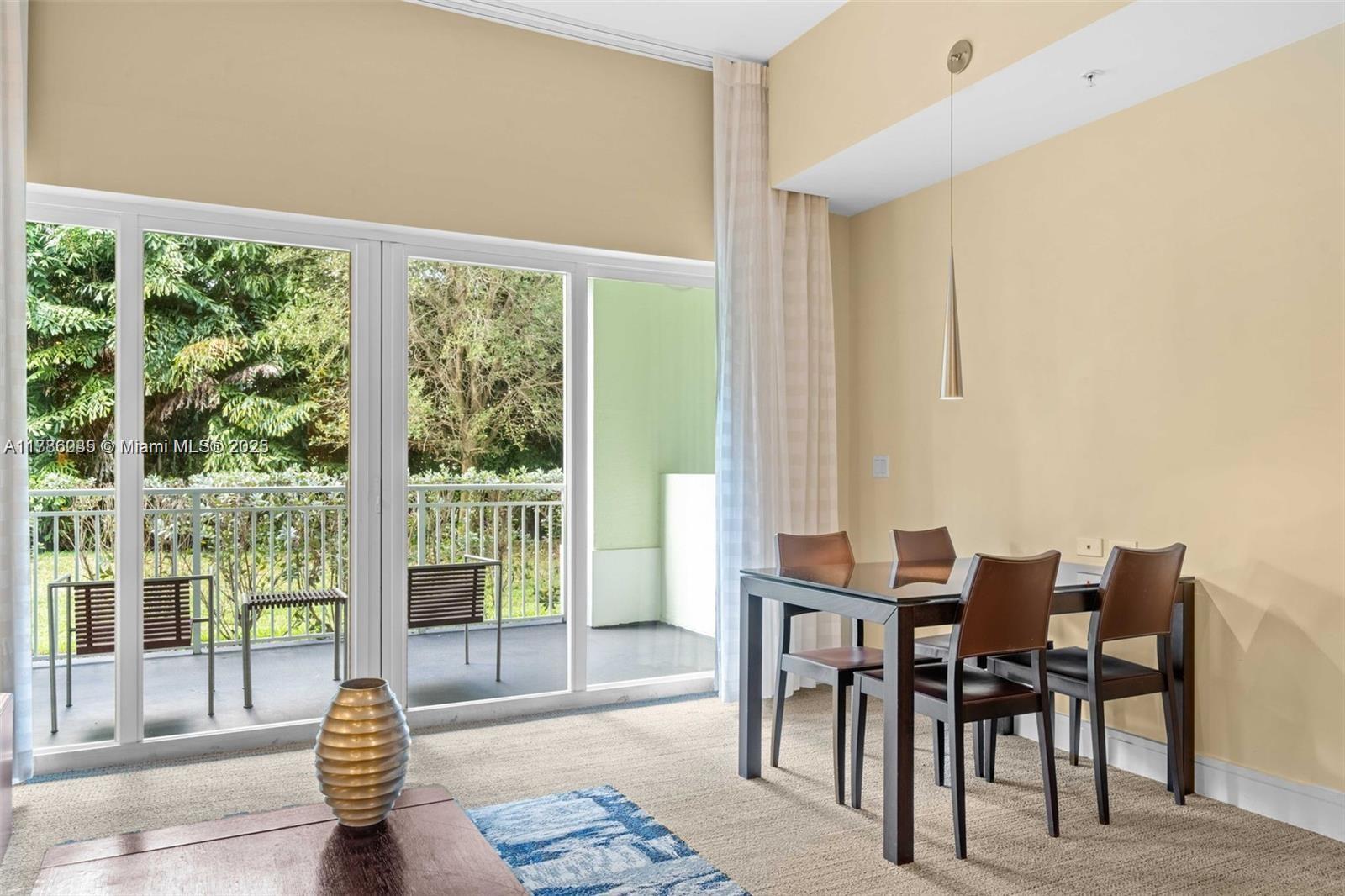 A dining area with a glass table and chairs sits beside a sliding glass door — 5300 NW 87th Ave # 115, Doral FL 33178, DORAL, FL