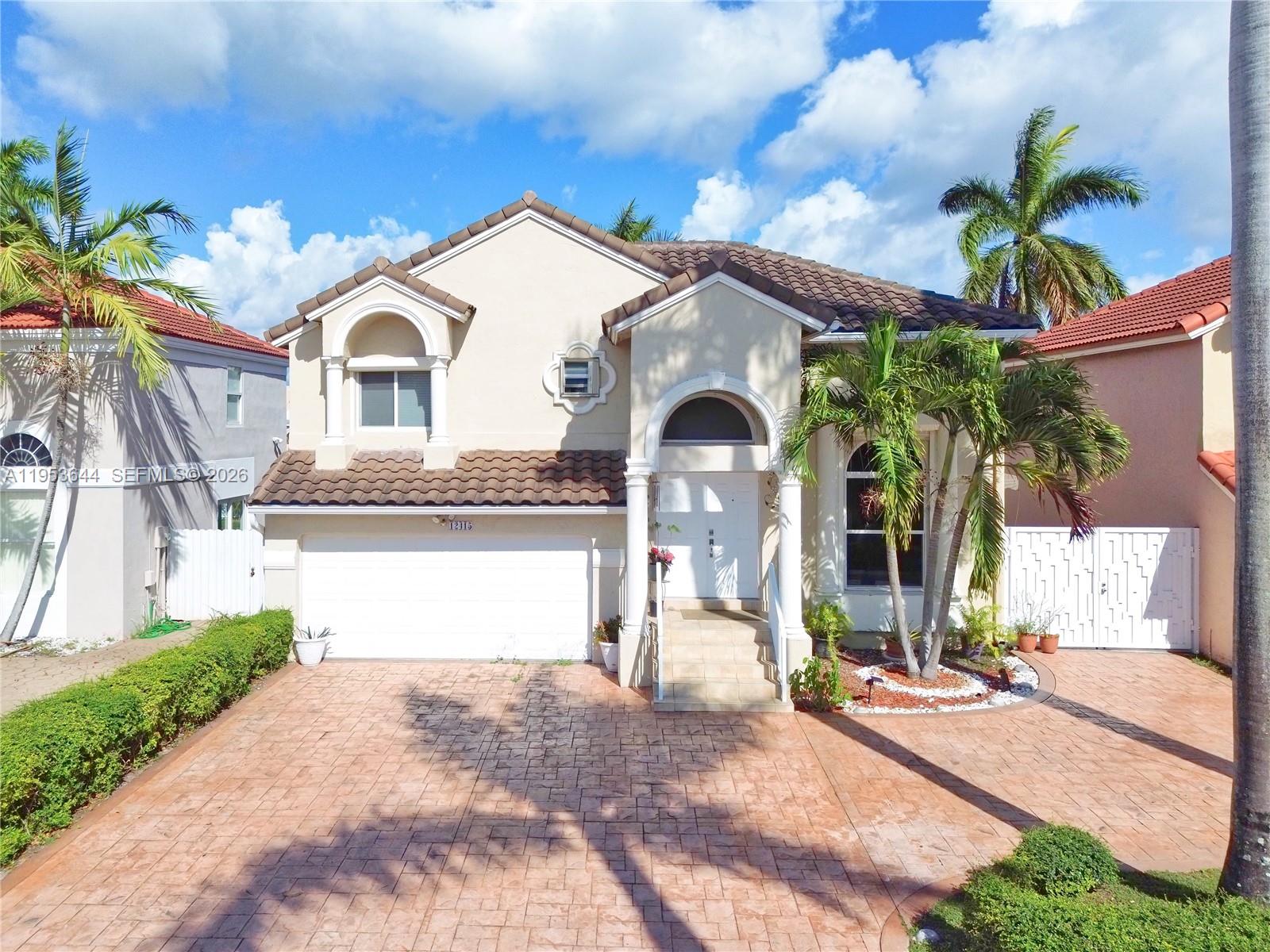 A two-story house with a tiled roof, white garage, and a paved driveway — 12415 NW 7th St, Miami FL 33182, MIAMI, FL