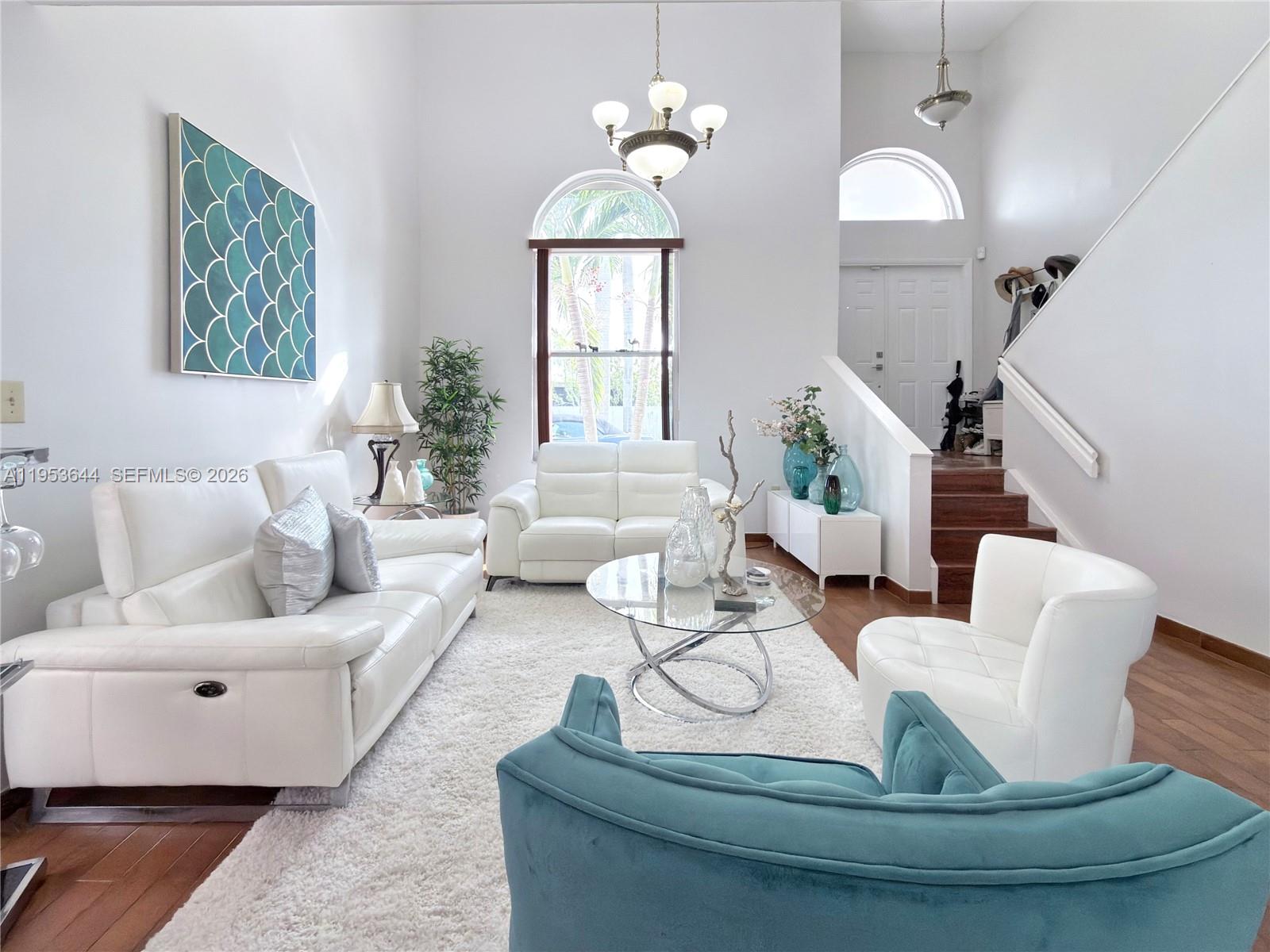 A bright living room features white leather furniture, a glass coffee table, and high ceilings — 12415 NW 7th St, Miami FL 33182, MIAMI, FL