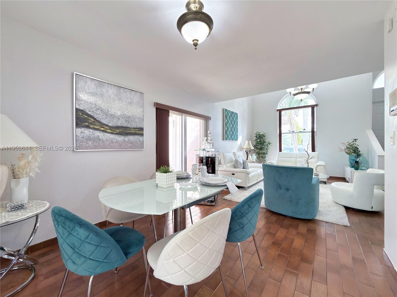 A dining area with a glass table and velvet chairs opens into a bright living room — 12415 NW 7th St, Miami FL 33182, MIAMI, FL