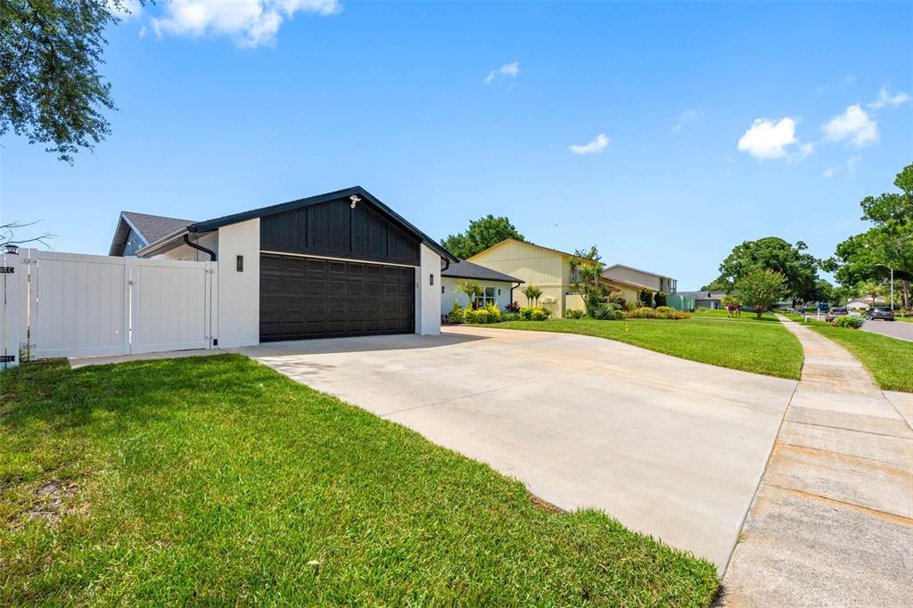 A white house with a black garage door and a white privacy fence — 16206 W COURSE DRIVE, TAMPA, FL