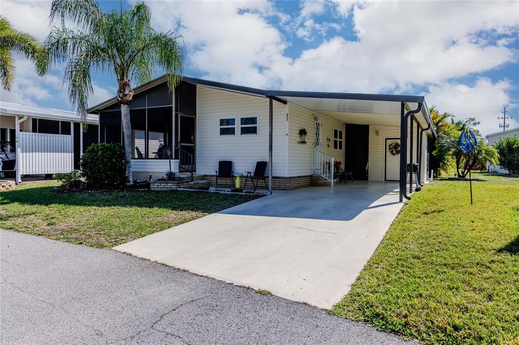 A single-story manufactured home features a carport, a screened porch, and a concrete driveway — 2100 KINGS HIGHWAY UNIT 653, PORT CHARLOTTE, FL