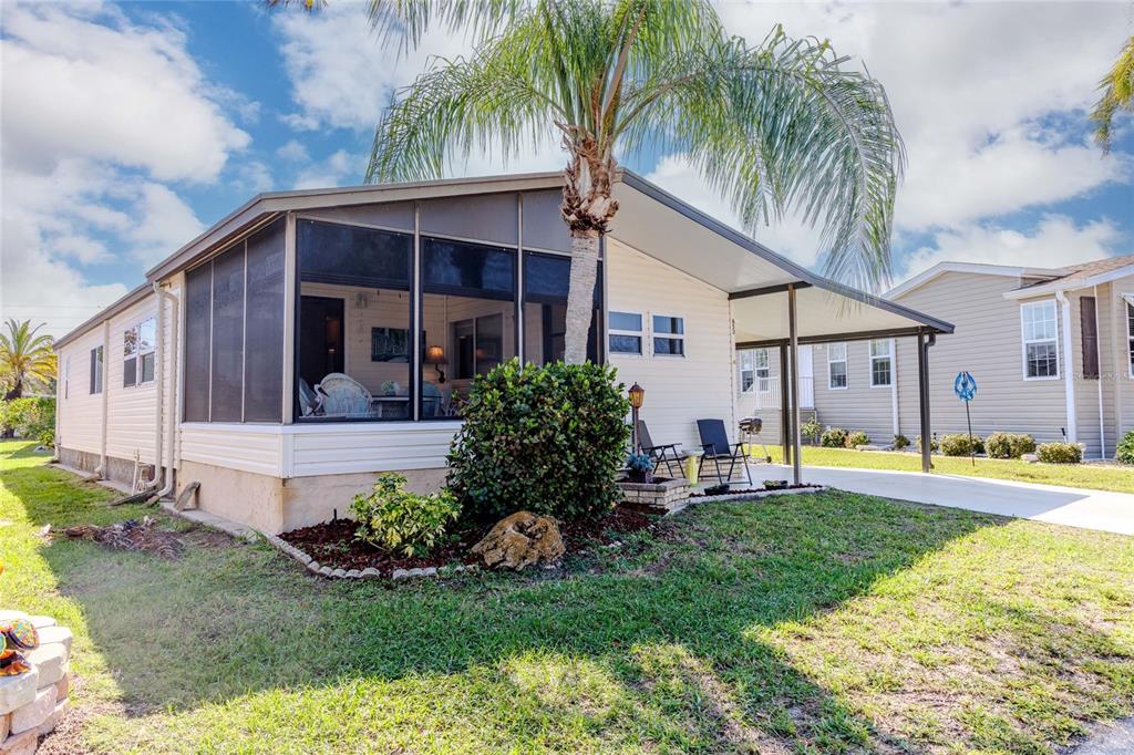 A mobile home with a screened-in porch, a carport, and a palm tree in front — 2100 KINGS HIGHWAY UNIT 653, PORT CHARLOTTE, FL