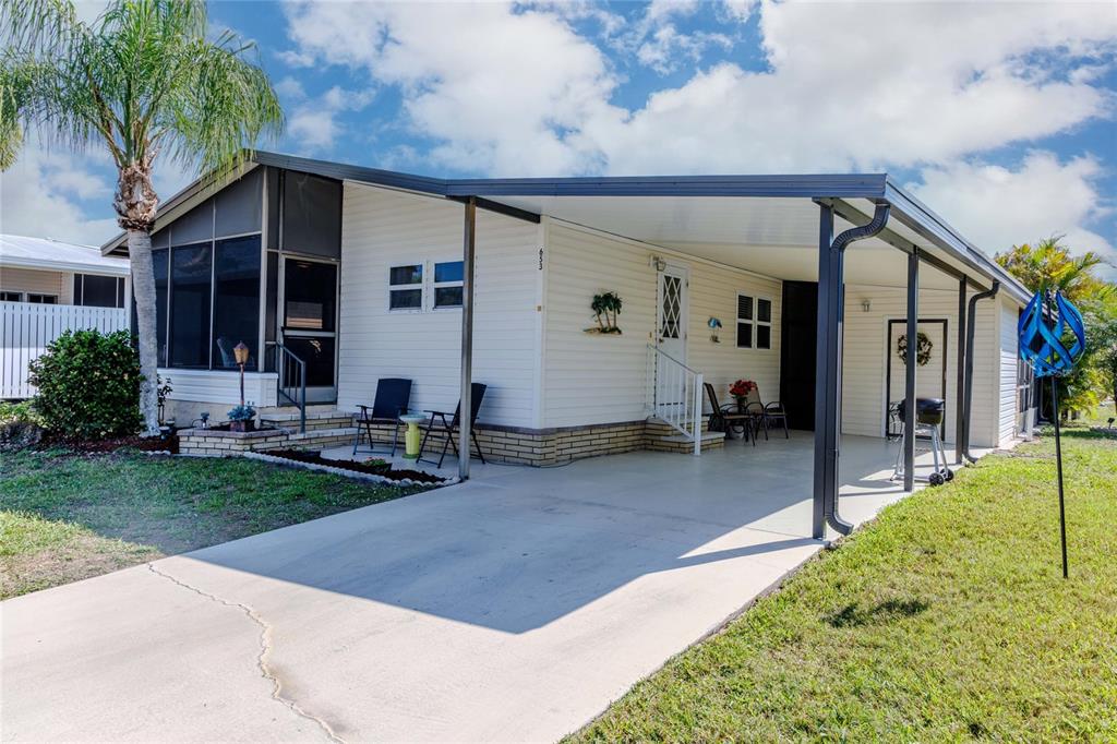A single-story manufactured home features white siding, a screened-in porch, and a covered carport — 2100 KINGS HIGHWAY UNIT 653, PORT CHARLOTTE, FL