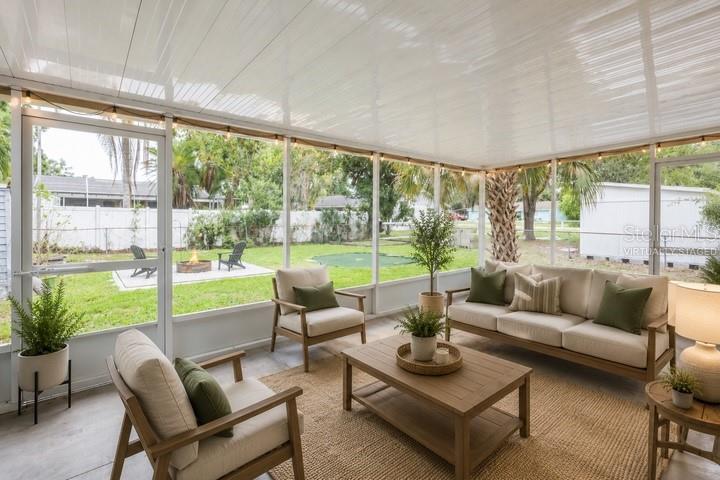 A screened-in porch features a sofa, armchairs, a coffee table, and a view of a yard — 314 4TH AVENUE SW, RUSKIN, FL