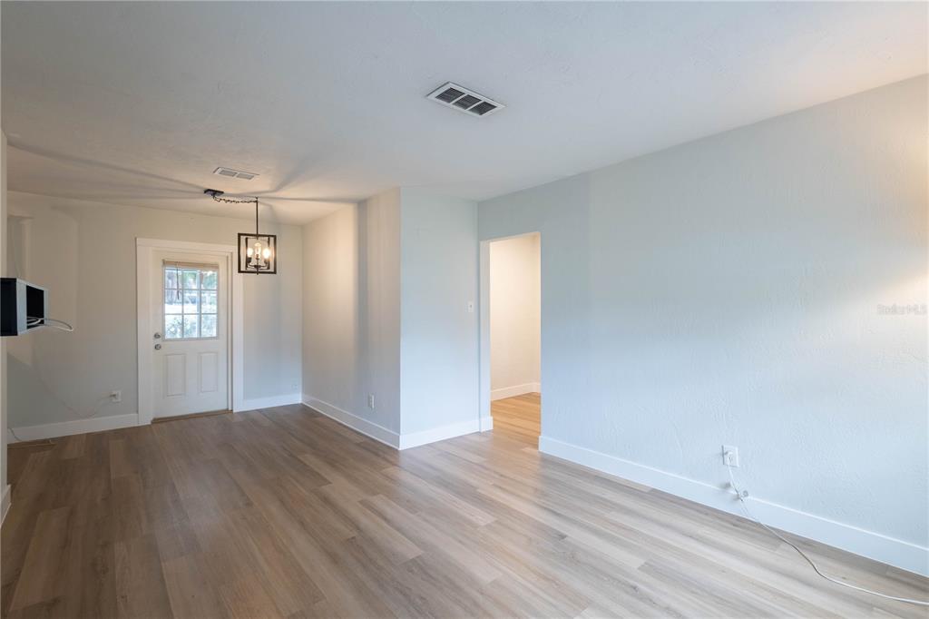 An interior view shows a room with light-colored walls, wood-look flooring, and a glass-paneled door — 314 4TH AVENUE SW, RUSKIN, FL